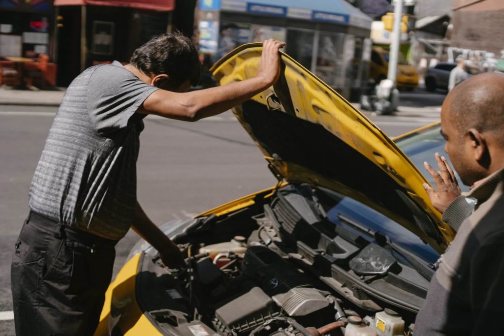 a man checking on his car alternator and car battery